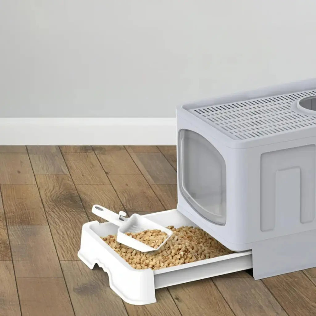 Cat litter box with a scoop on a wooden floor