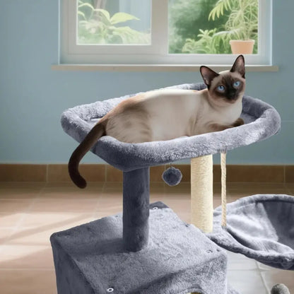 Cat sitting on a gray cat tree with a window and plants in the background