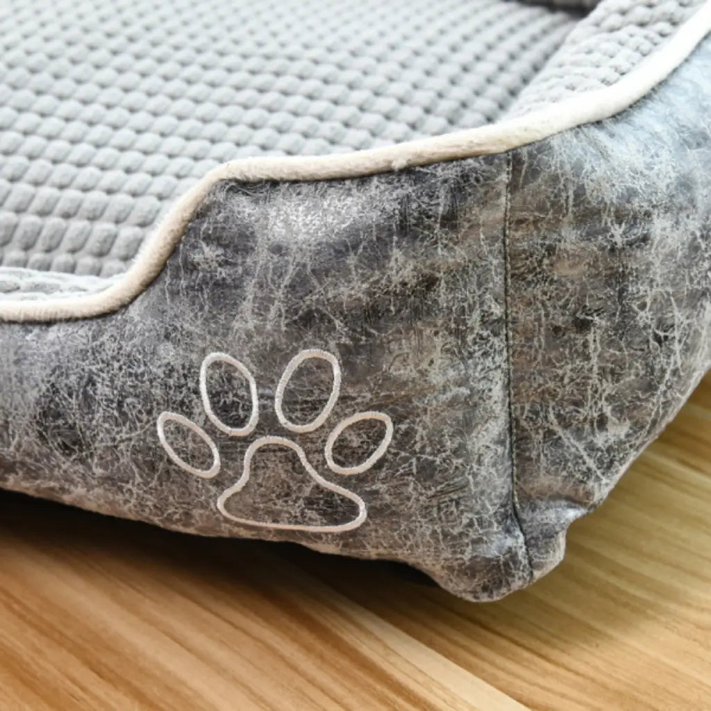 Close-up of the grey reversible pet sofa bed showing embroidered paw detail and textured corn velvet interior