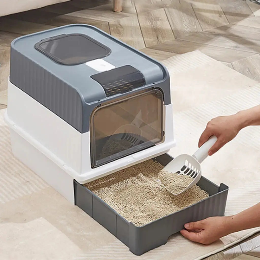 Pet litter box with a scoop on a wooden floor