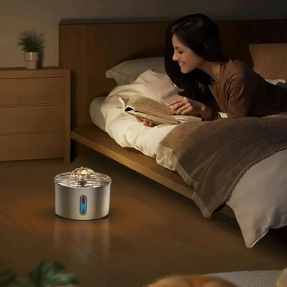 Woman reading a book in bed with a night light on a wooden nightstand, while a water fountain silently pouring water next to her